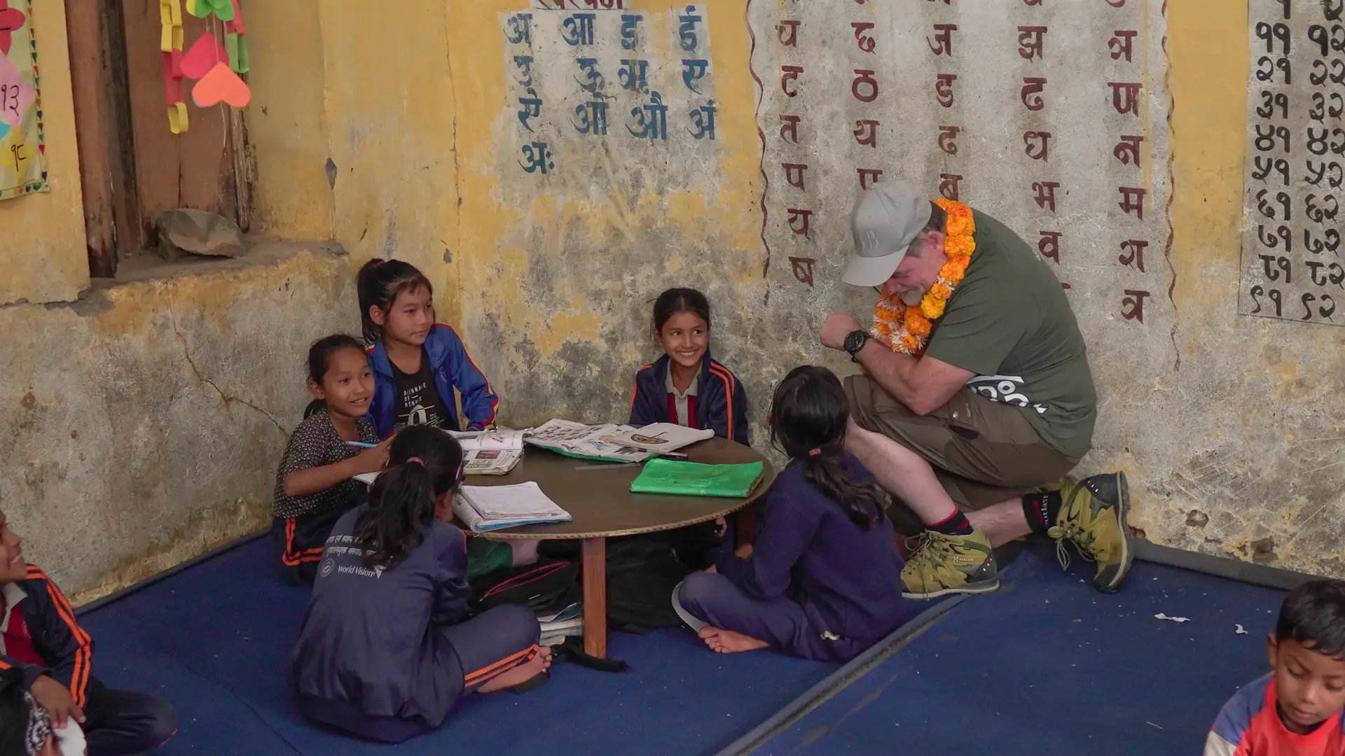 Man sitter med två barn i skolan