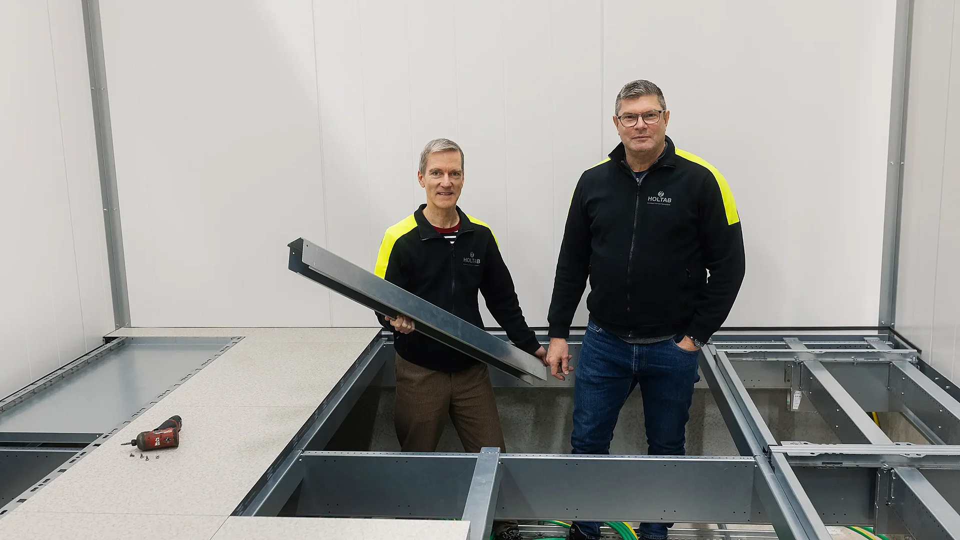 Två i Holtabs personal står i lucka i golvet på teknikhus