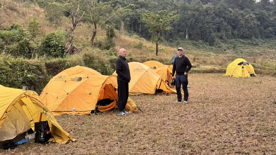 Två män framför gula tält på ett fält i Nepal